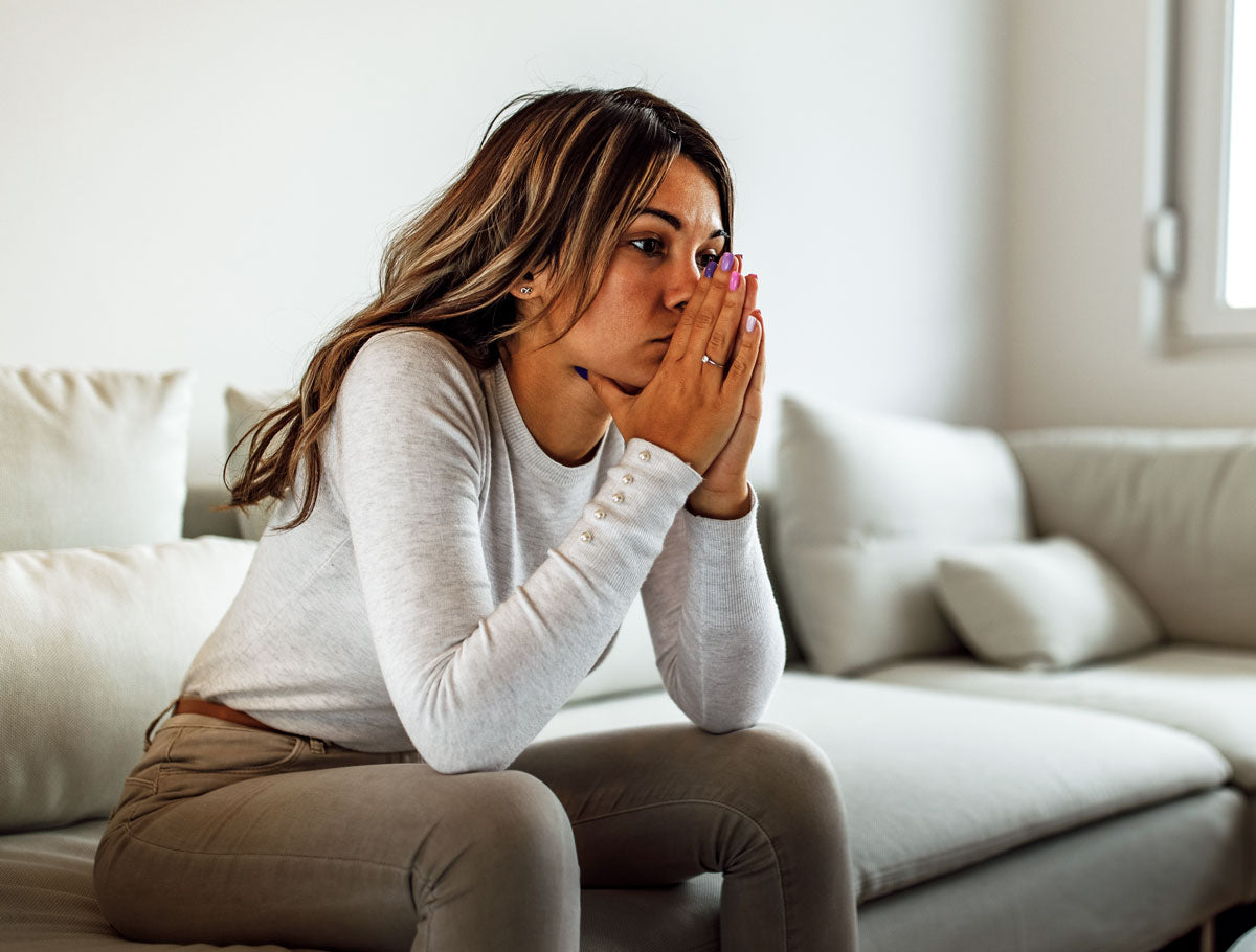 Upset mother holding her hands in front of her face looking off