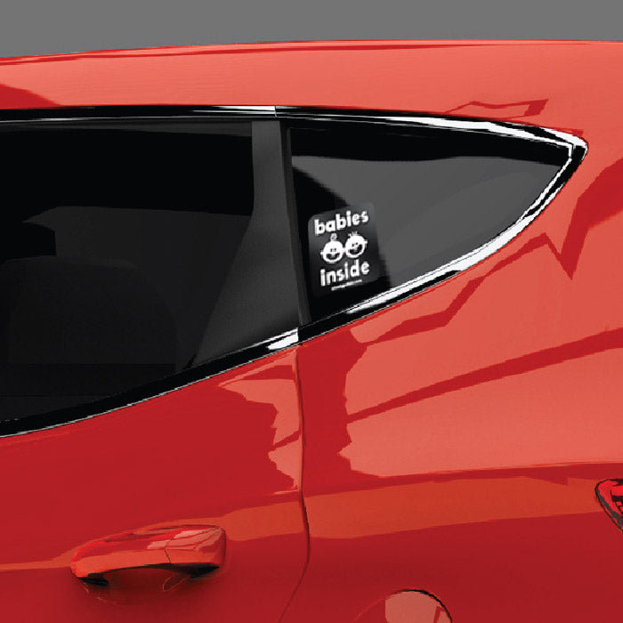 Close up of Babies Inside side sticker on a tinted side window on a red SUV.