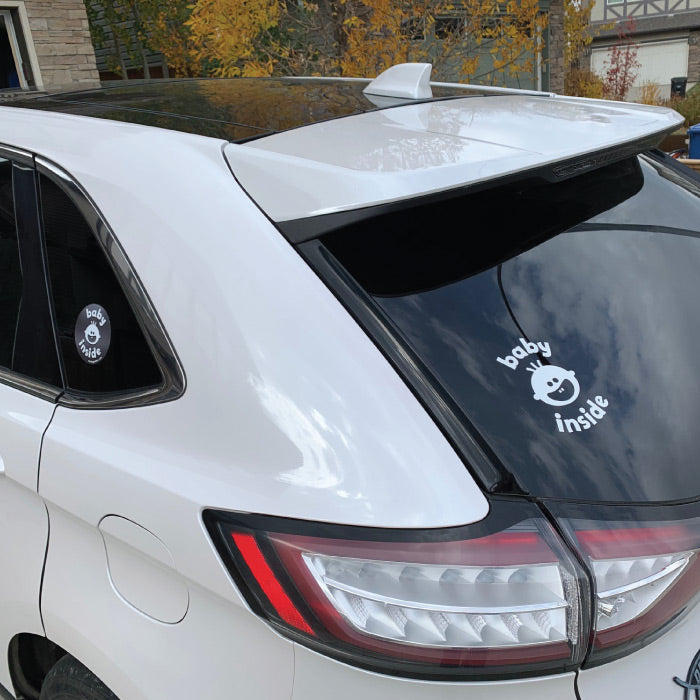 Close up of 'Baby Inside' large white decal on rear tinted window and left side sticker on tinted side window.