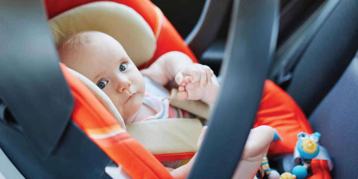 Picture of a young sweet baby in their carseat inside a car.